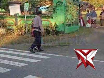 Bhabinkamtibmas Desa Tobe Bripka I Komang Kariasa Membantu Menyebrangkan Anak Pergi Sekolah