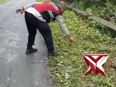 Bhabinkamtibmas negeri Ihamahuw membantu warga memotong rumput di pinggir jalan